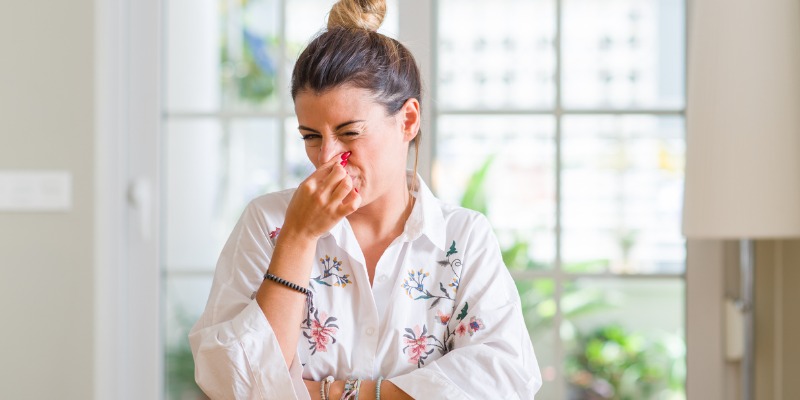 young woman plugging her nose because of bad smell